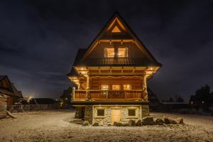 a log cabin with a balcony at night at Domek Na Przełęczy wood house & mountain view in Murzasichle