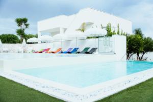 a swimming pool with chairs next to a building at Tuo Hotel in Polignano a Mare