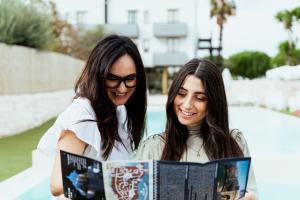 two women are reading a book together at Tuo Hotel in Polignano a Mare