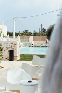 a table with white chairs and a swimming pool at Tuo Hotel in Polignano a Mare