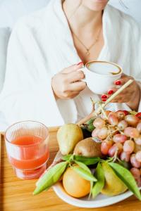 a woman sitting at a table with a plate of fruit at Tuo Hotel in Polignano a Mare