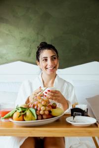 a woman sitting at a table with a plate of fruit at Tuo Hotel in Polignano a Mare