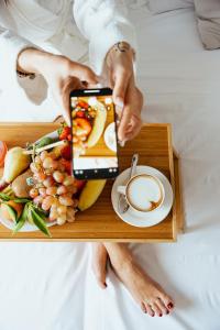 a person holding a tray with a plate of food and a cup of coffee at Tuo Hotel in Polignano a Mare