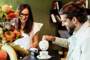 a woman pouring a man a cup of coffee at Tuo Hotel in Polignano a Mare