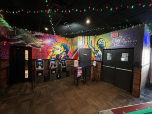 a room with four video poker machines and a colorful wall at Commercial Hotel in Edmonton