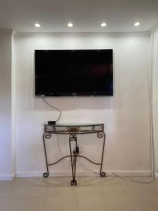 TV de pantalla plana colgada en una pared blanca en Casa tranquila 500 metros da praia do campeche en Florianópolis
