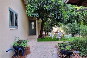 a patio with chairs and a table and a tree at השיטה 5 in Rosh Pinna