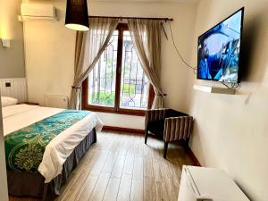 a bedroom with a bed and a tv on a wall at Hotel Boutique Casa Noble in Santiago