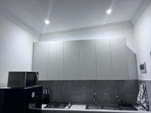 uma cozinha com armários brancos, um lavatório e uma televisão em Beevap Guesthouse em Pretoria