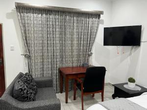 a living room with a desk and a couch and a television at Beevap Guesthouse in Pretoria