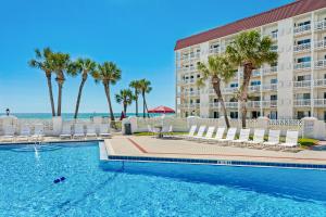 a swimming pool in front of a hotel with palm trees at El Matador 119 in Fort Walton Beach