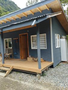 ein blaues Haus mit einer Veranda und einer Terrasse in der Unterkunft Cabañita Sustentable El Este Cochamó in Cochamó