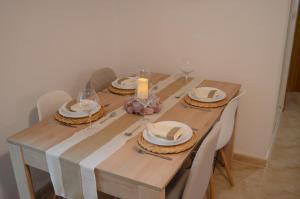 una mesa de madera con platos y vasos y una vela en Dunas de Águilas, en Águilas