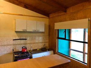 a kitchen with a stove and a sink and a window at Cabañas Vista al Paine in Torres del Paine