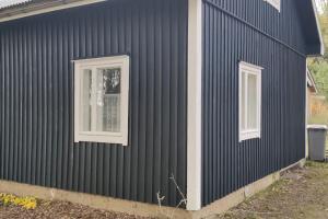 a black house with two windows on the side of it at Villa Pikkumustikka in Töysä