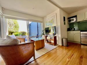 a living room with a large window and a kitchen at Watermark Apartments in Oneroa