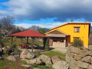 una casa amarilla con un cenador en un campo en Casa Rural Naranja, en El Tiemblo