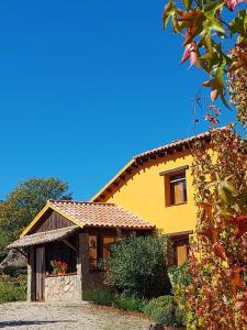 Casa amarilla con techo de baldosa en Casa Rural Naranja, en El Tiemblo