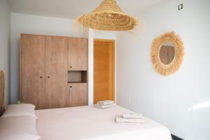 een witte kamer met een bed, een spiegel en een plank bij Ocean View Penthouse El Cotillo in Cotillo