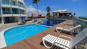 einen Pool mit Chaiselongues neben einem Gebäude in der Unterkunft Areias do Mar Aconchegante e Tranquilo com Varanda in Barra de São Miguel