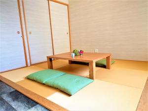 京都的住宿－GLANZ KEI Kyoto Station，一间房间,地板上设有一张桌子和一个绿色枕头