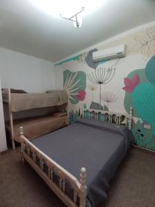 1 dormitorio con 1 cama y una pared con flores en La Retoña en Cerrillos