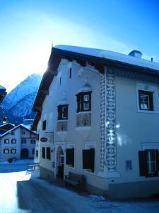 a large white building with snow on the ground at Hotel Engiadina in Scuol