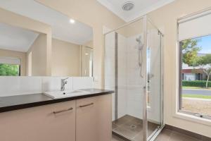 y baño blanco con lavabo y ducha. en Charming 4 bedrooms house in Truganina /Williams Landing, en Laverton