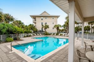 a swimming pool with chairs and a building in the background at Gulf Island 412 in Navarre