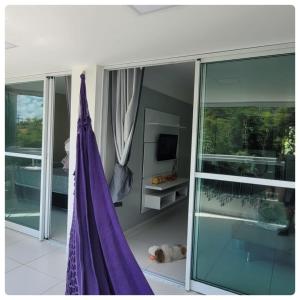 コンデにあるBRISA DE CARAPIBUSのガラスドアと紫のカーテンが備わる部屋
