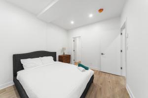 een slaapkamer met een groot wit bed met witte lakens bij Stonewall Suites in Montreal