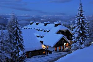 une maison recouverte de neige la nuit dans l'établissement Alpenhotel Marcius, à Sonnenalpe Nassfeld