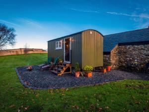 a green tiny house with a stone wall at The Pleasant Hut at MountPleasant Farm in Ulverston