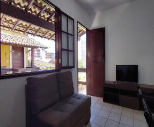 ein Wohnzimmer mit einem Sofa und einem TV in der Unterkunft Excelente apt 03 qts - Cabo Frio Braga Praia do Forte - caução garantia de 400,00 - WiFi grátis - ar condicionado em dois quartos in Cabo Frio