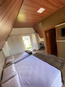 a bedroom with two beds and a wooden ceiling at Chalezinho Pousada in Brumadinho
