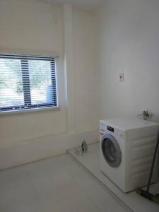 - un lave-linge dans une chambre blanche avec fenêtre dans l'établissement The Willow Apartment, à Clifton Falls