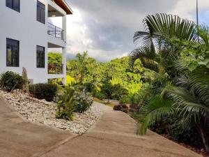 a walkway next to a white building with palm trees at The Willow Apartment in Clifton Falls