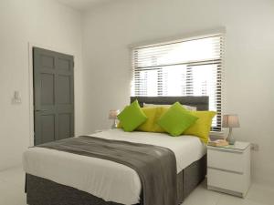 Un dormitorio con una cama con almohadas amarillas y una ventana en The Willow Apartment, en Clifton Falls
