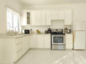 a white kitchen with white cabinets and a refrigerator at The Willow Apartment in Ocho Rios
