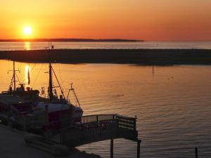 um barco está ancorado ao lado de uma doca ao pôr-do-sol em 5 star holiday home in Wendtorf em Wendtorf