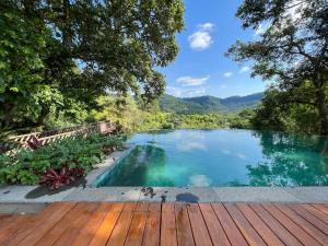 une piscine avec une terrasse en bois et un lac dans l'établissement Pousada Vale do Dinossauro, à São Pedro