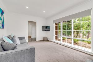 a living room with a couch and a large window at Hahndorf Creek Retreat in Hahndorf