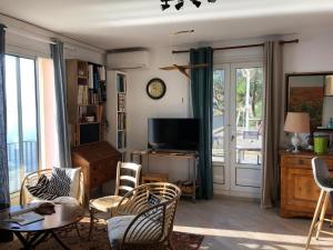 Une grande terrasse sur la mer في Brando: غرفة معيشة مع طاولة وكراسي وتلفزيون