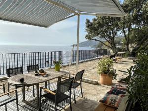 Une grande terrasse sur la mer في Brando: فناء مع طاولة وكراسي والمحيط