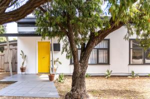 een huis met een gele deur en een boom bij The Piccolo Shack in Gracetown