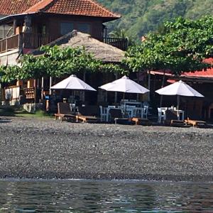 a resort with tables and umbrellas on a beach at Amed Sunset Beach in Amed
