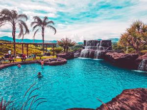 a pool with a waterfall and people in the water at Chalezinho Pousada in Brumadinho