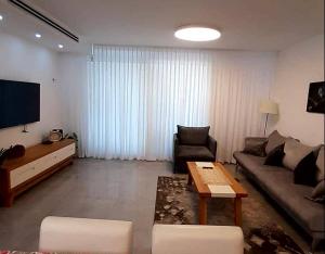 uma sala de estar com um sofá e uma televisão em King David breathtaking LAKE VIEW 4BDR PENTHOUSE em Tiberias
