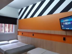 um quarto com 2 camas e uma televisão de ecrã plano em Artsy Vitoria Hostel em Vitória