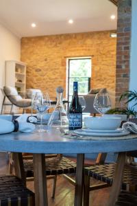 a table with glasses and a bottle of wine on it at Adelaide Hills Luxury Escape - 1884 Summertown in Summertown